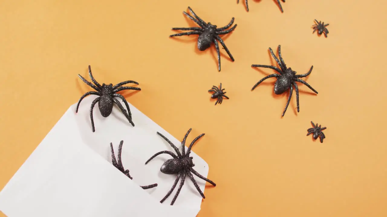 Multiple spider toys coming out of a envelope against orange background