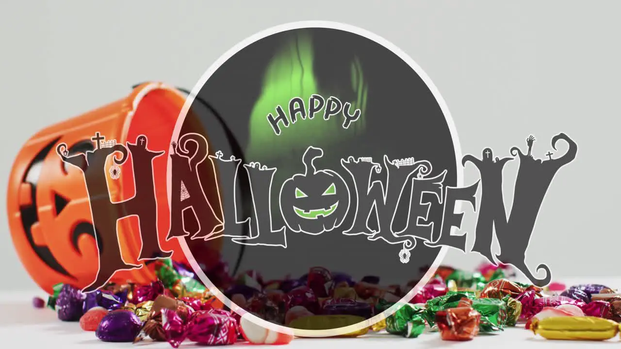 Happy halloween text banner against halloween candies fallen from pumpkin shaped bucket