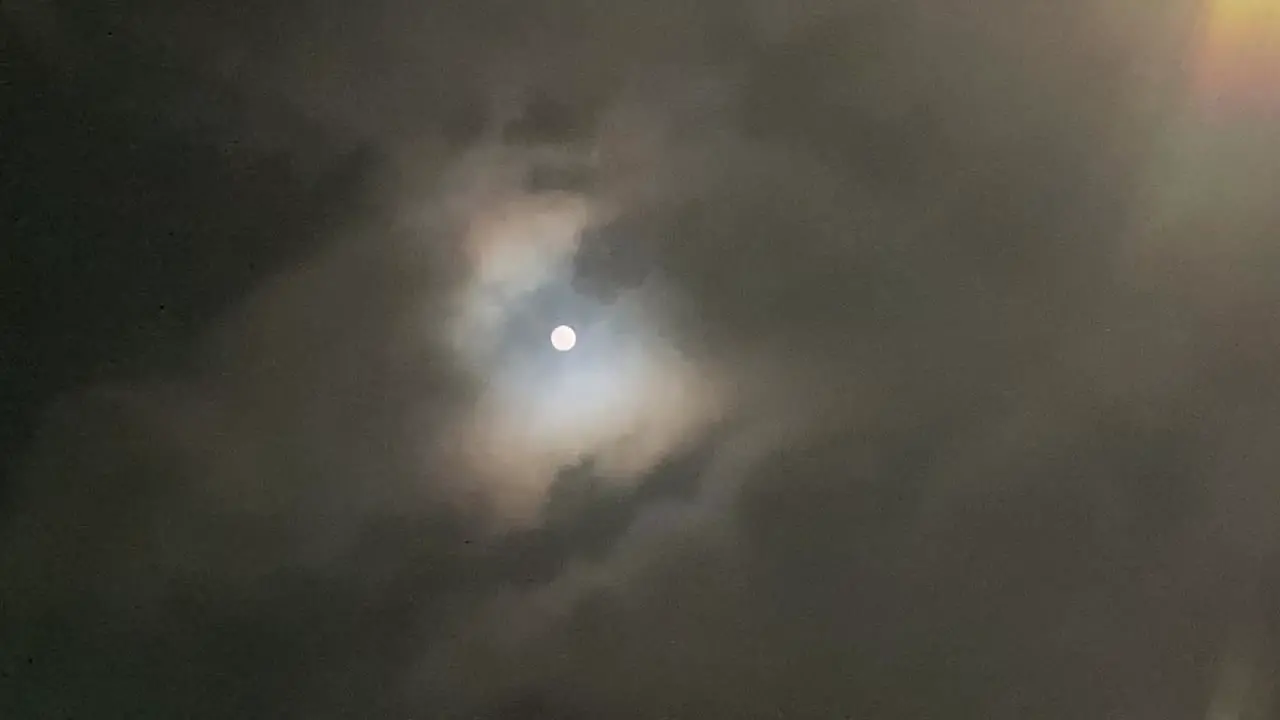 closeup of the full moon in the dark covered by the cloud not fully covered