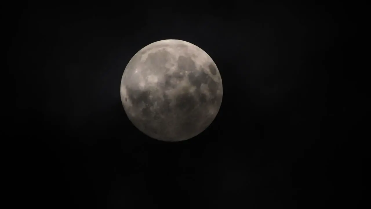 Clouds passing by the full moon real time shot