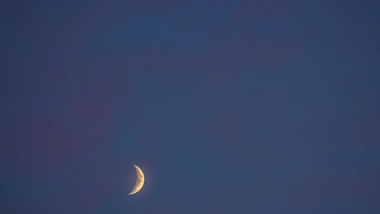 Timelapse shot of beautiful crescent moon moving isolated against dark black sky background at night time