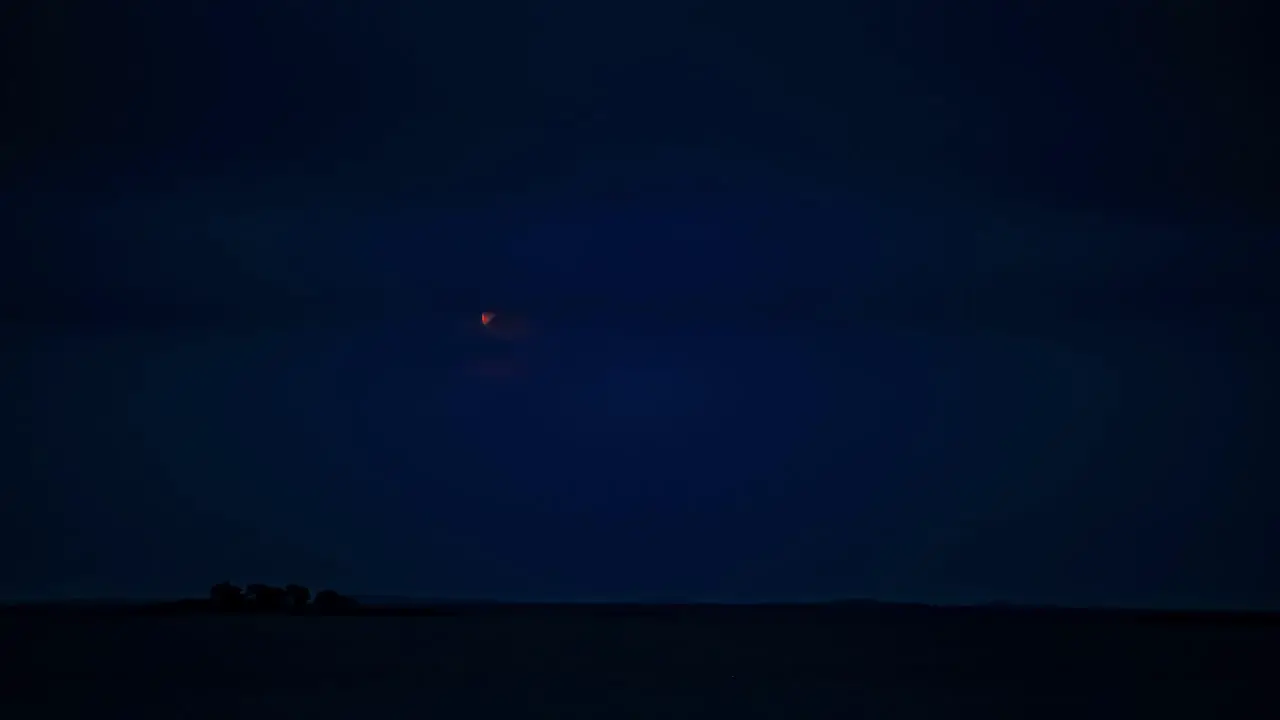 The waxing gibbous moon rises through the nighttime clouds time lapse