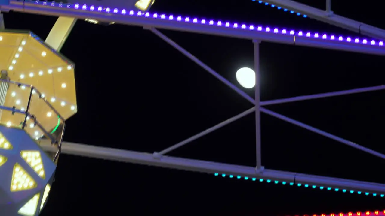 Ferris Wheel Attraction Spinning with Moon in the Background Evening Night Close Up