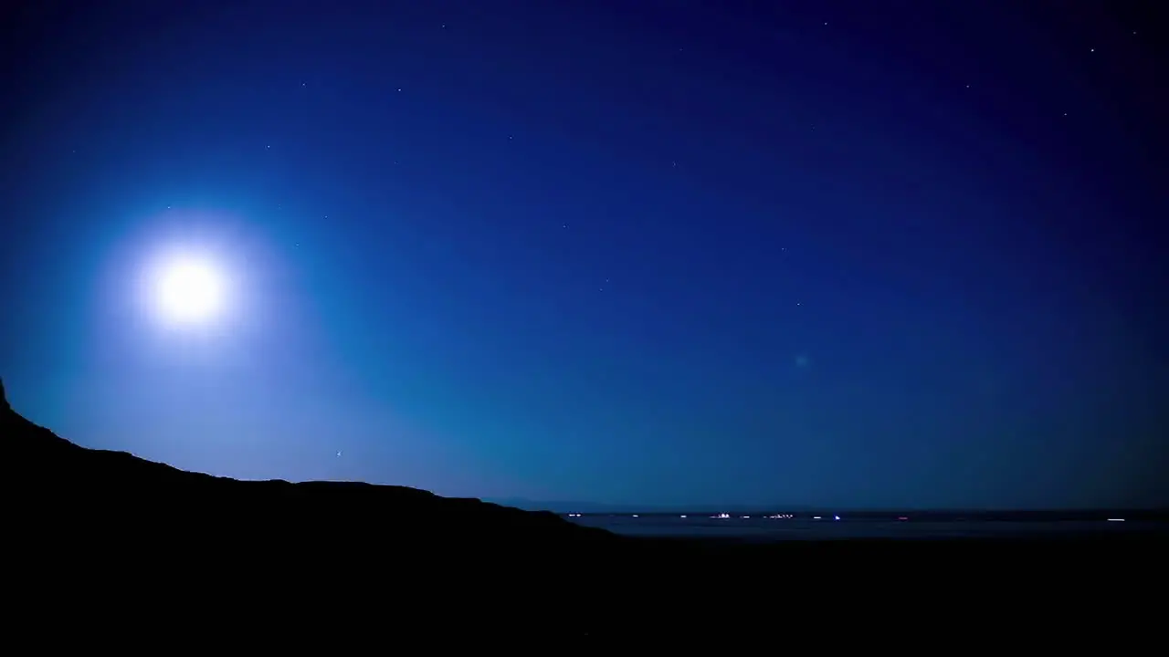 Time lapse of the moon rising above a distant highway in the desert at night