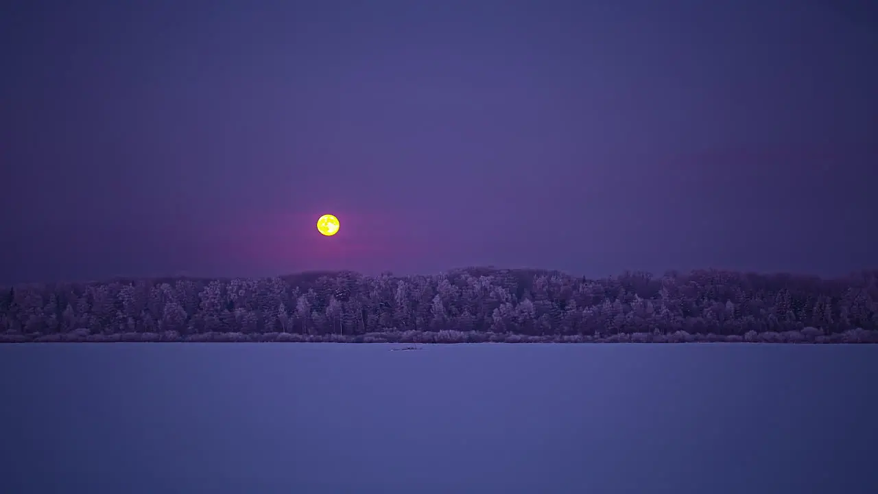 Full moon rising beyond a frozen lake and forest dreamy time lapse