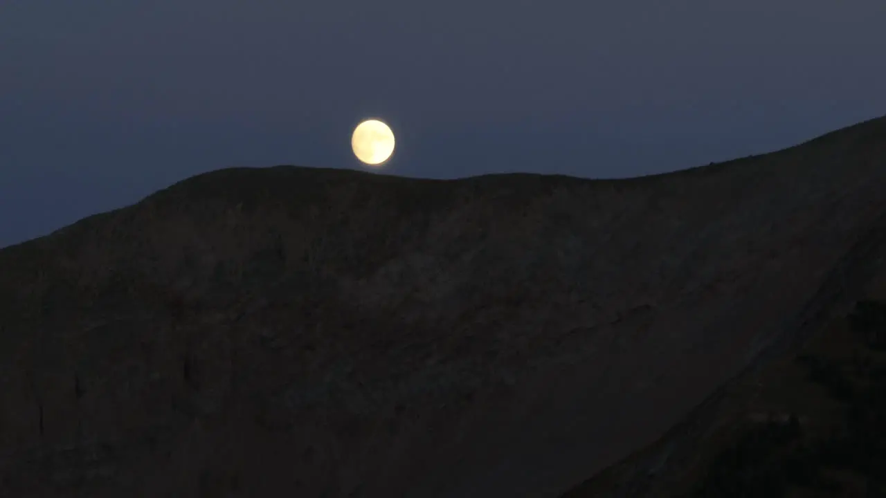 Aerial view of a ridge line and a full moon just above it in the Colorado Rockies