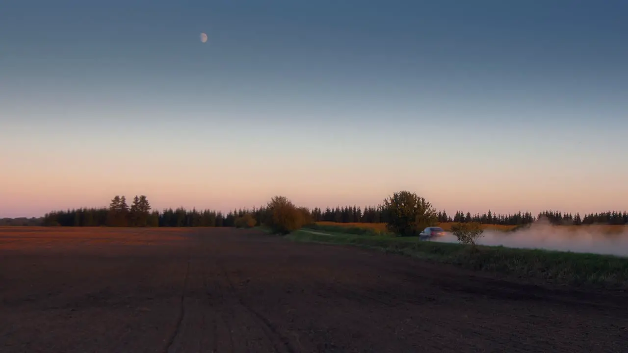 Evening view of fast driving car on a dusty road