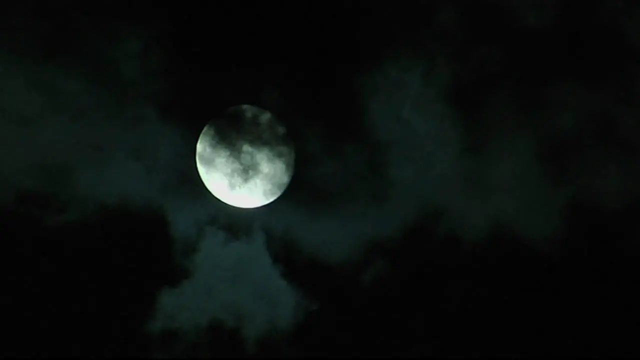 Clouds pass before a bright full moon