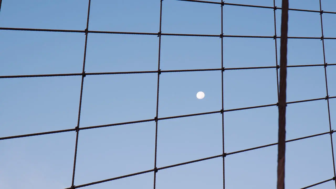 Majestic Moon in dark blue dawn sky view through cables of Brookly bridge