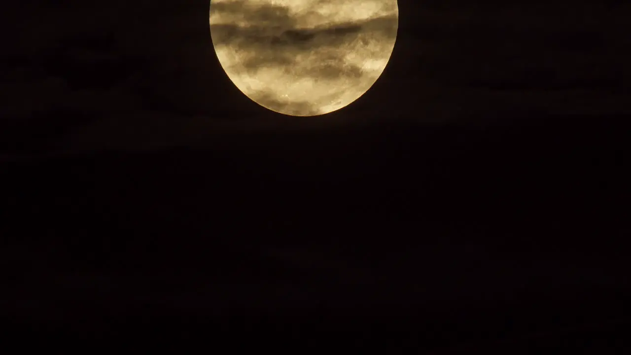 A timelapse shot of a cloud covered full moon dropping into frame static shot