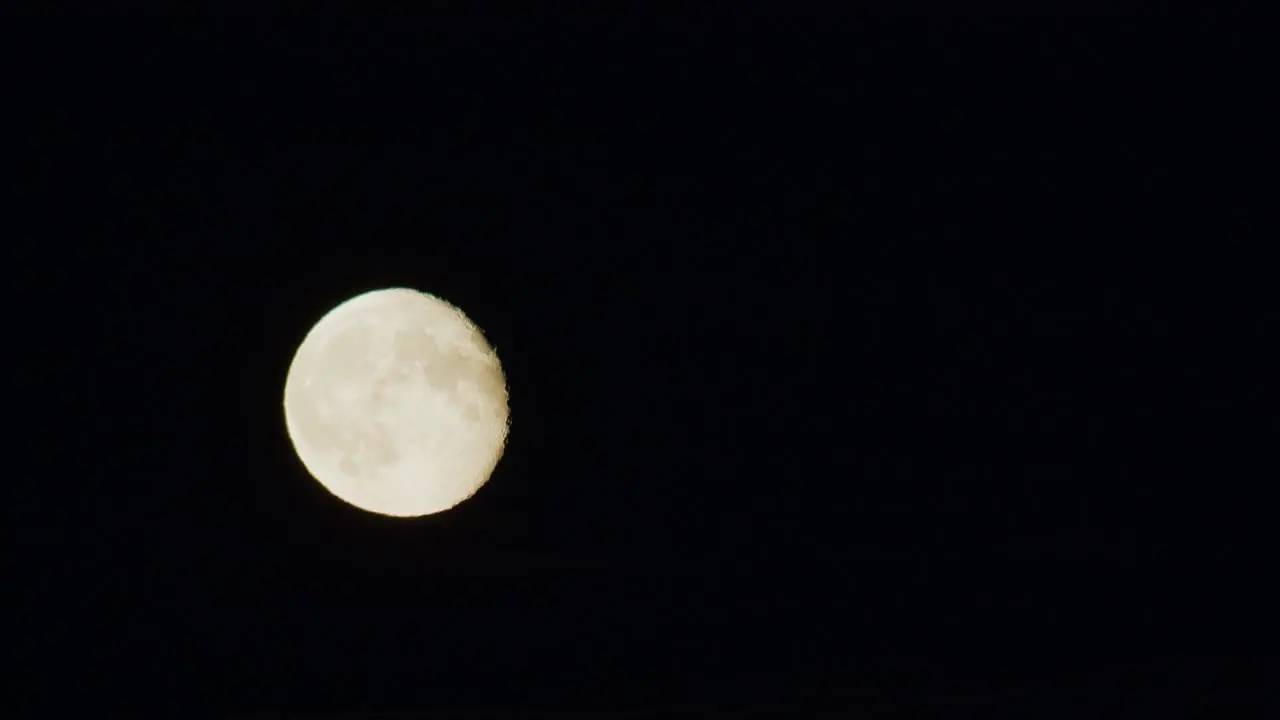 Dramatic low moon rise through thin cloud layer time lapse strong air disturbance