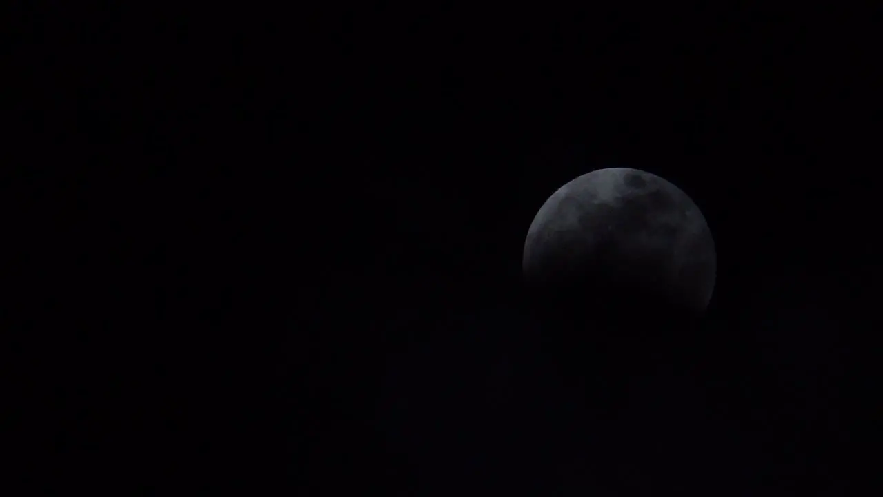 Clouds partially obscure a full moon during a lunar eclipse