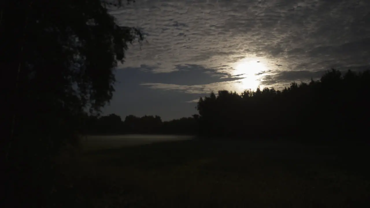 Cinematic mood Full moon time lapse as blanket of cloud sheet moves over rural countryside meadow