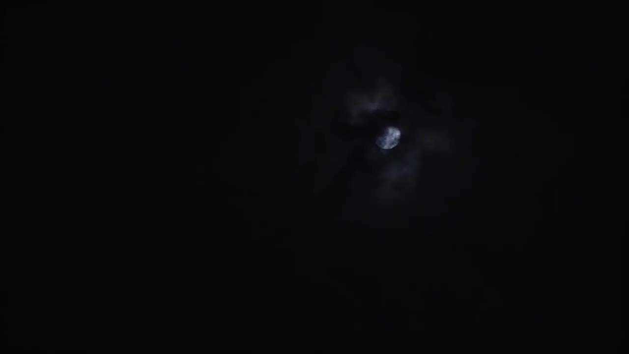 A full moon in the sky on an overcast night as the clouds move around the moon