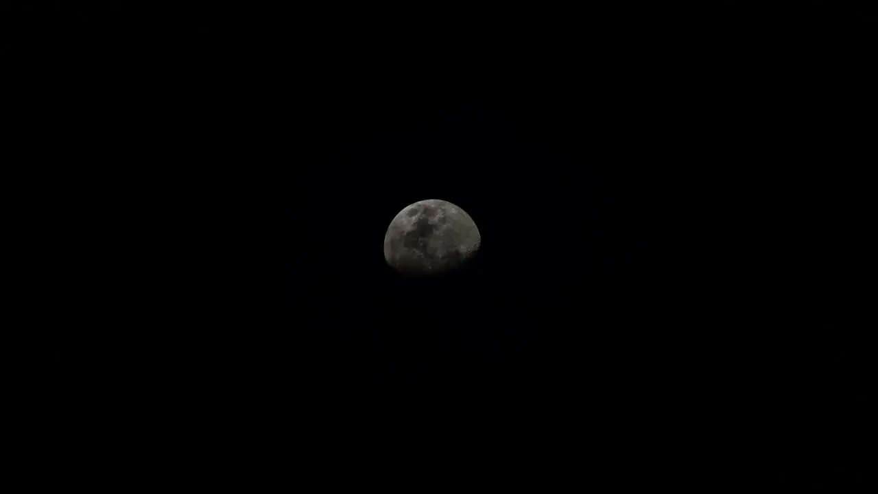 The waning gibbous moon crosses the sky with the silhouette of wispy clouds pass by long exposure time lapse