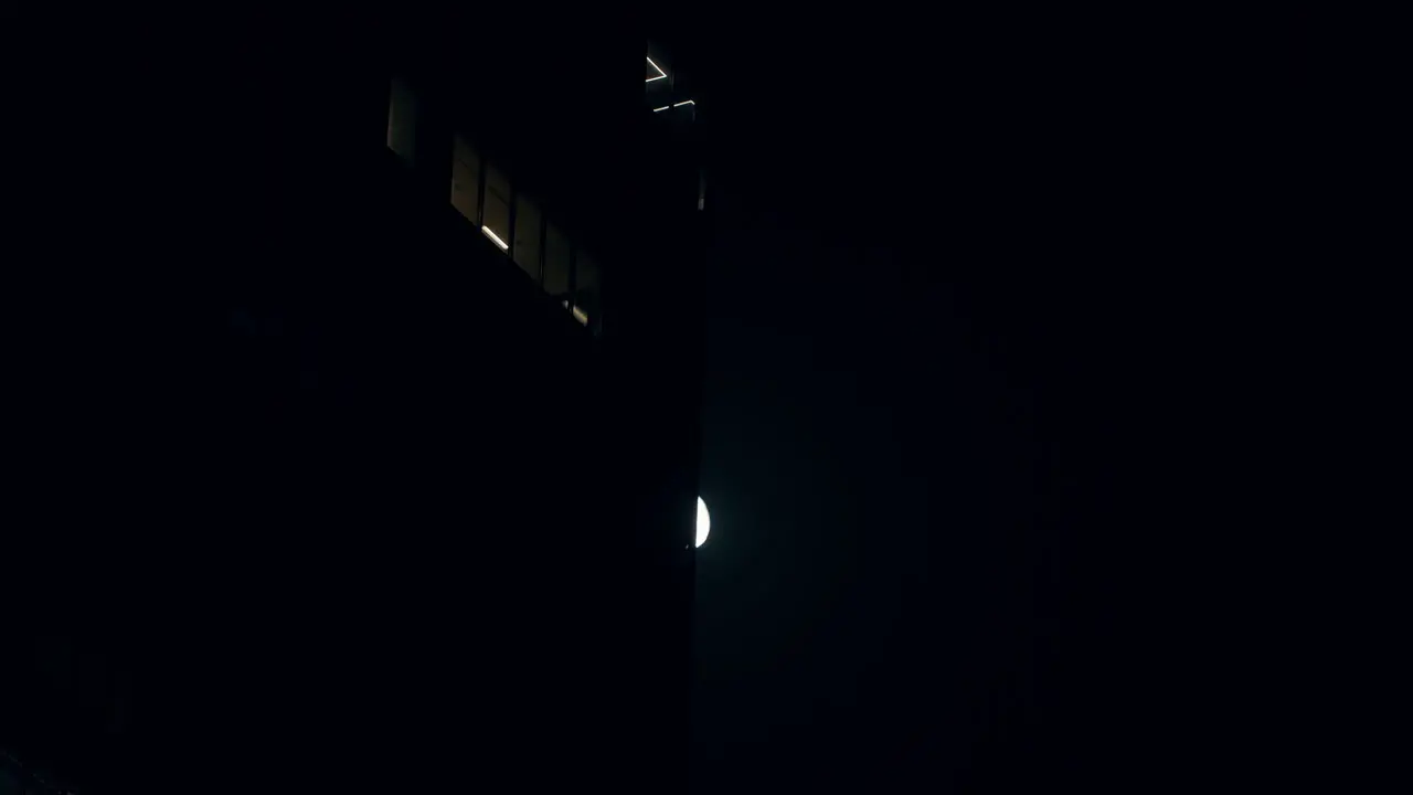 Bright Moon In The Night Sky Slowly Hiding Behind Building