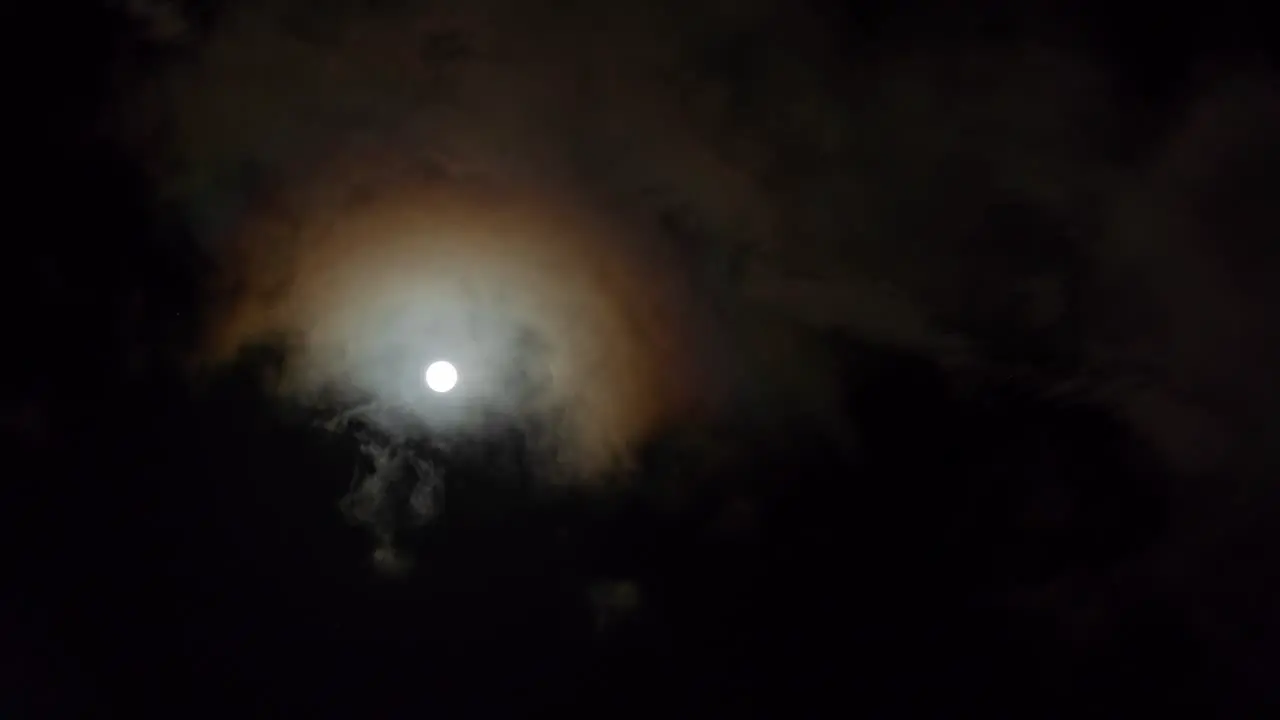 Bright glowing full moon with clouds passing in front looking up at night sky