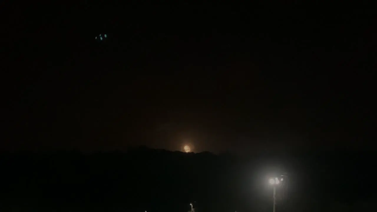 Full moon light through clouds at night over big mountains