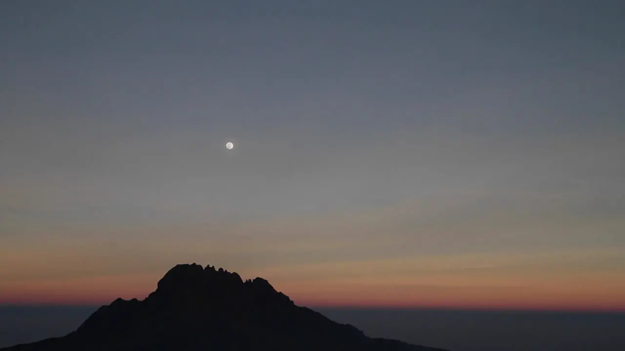 Moon over rocky outcrop at sunset