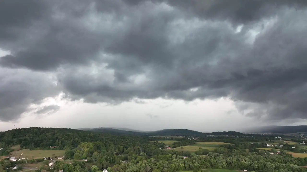 A rising aerial view of a big rainstorm moving over the countryside