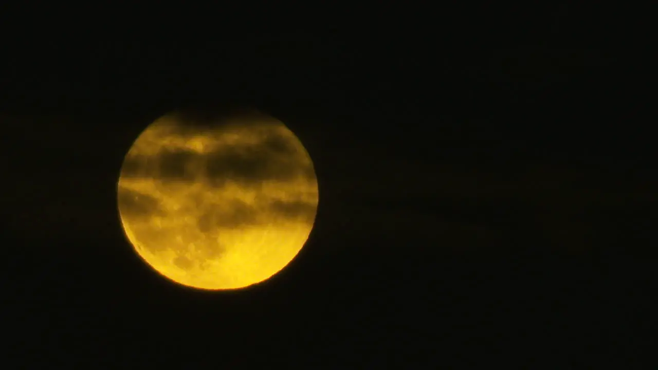 Stunning realtime long lens shot of a full moon with clouds passing in front