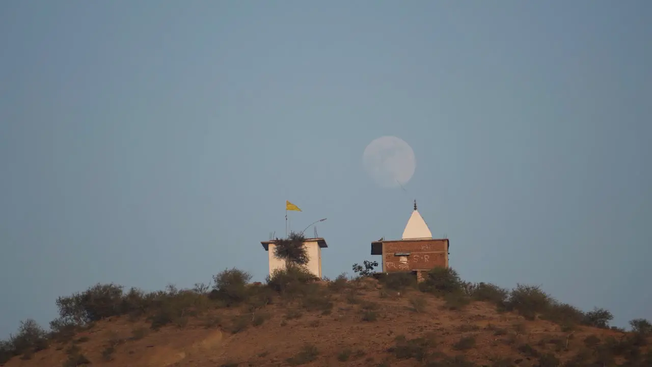 a Hindu temple on top of a hill with moon in background at a village of India