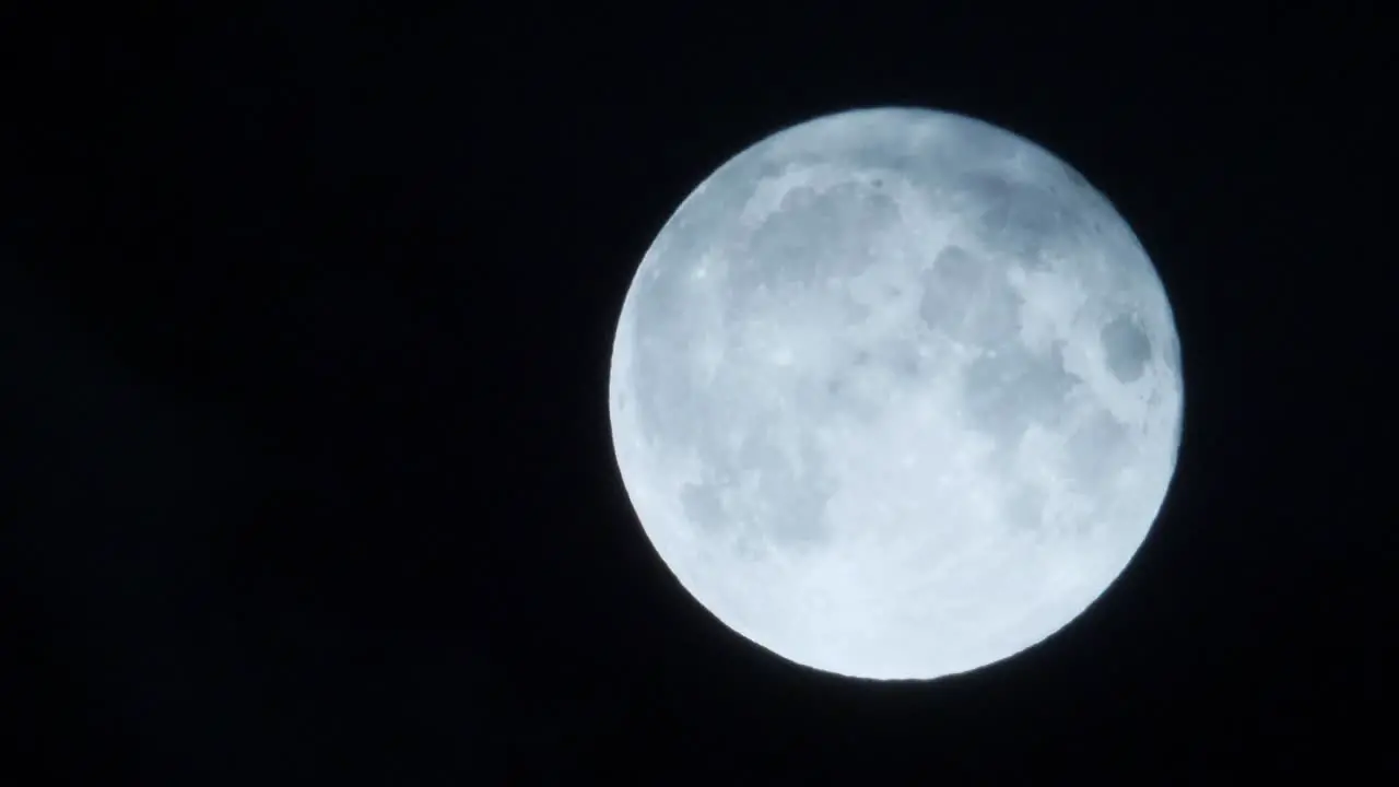 Full glowing moon with clouds covering blown by wind static dark sky backgroud