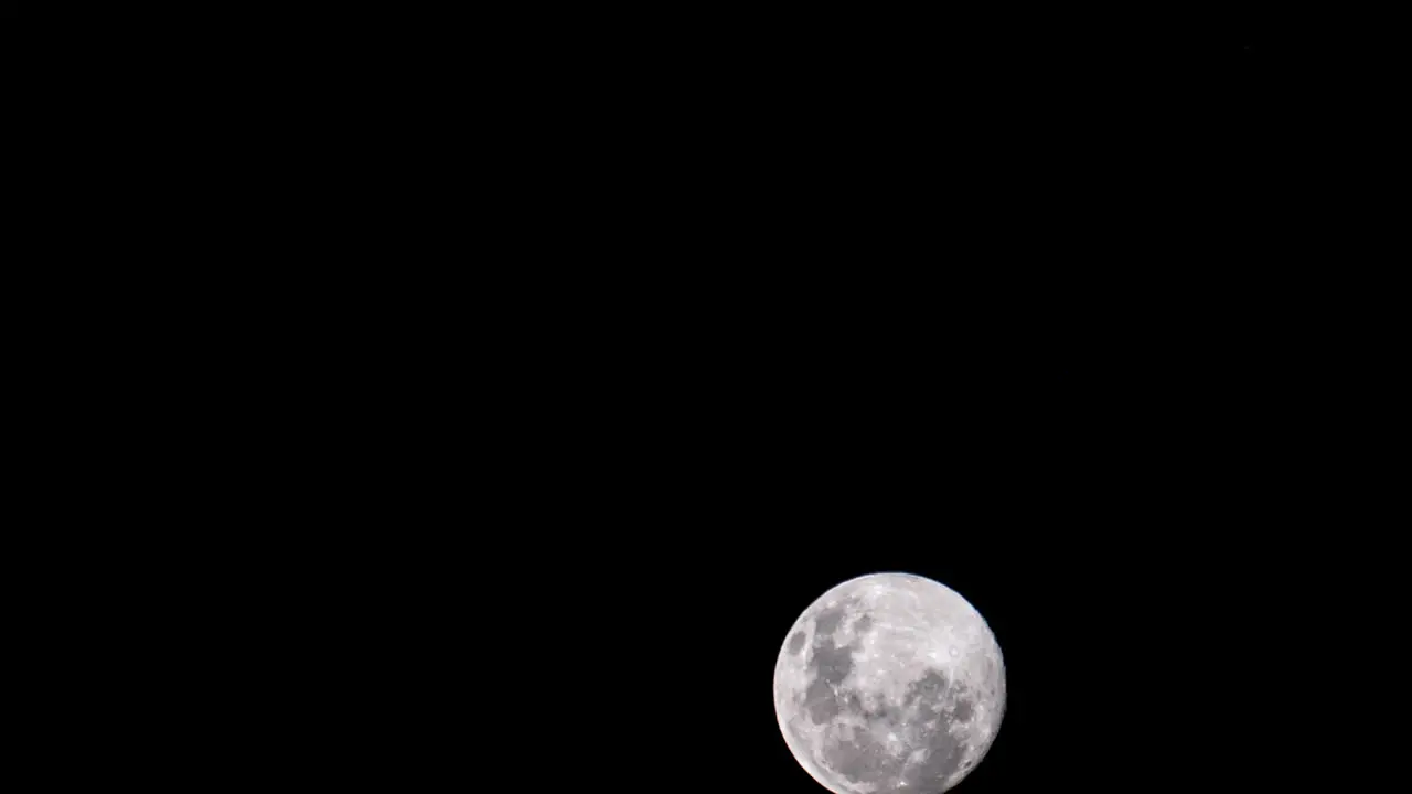 Timelapse of full moon close up rising through dark night sky