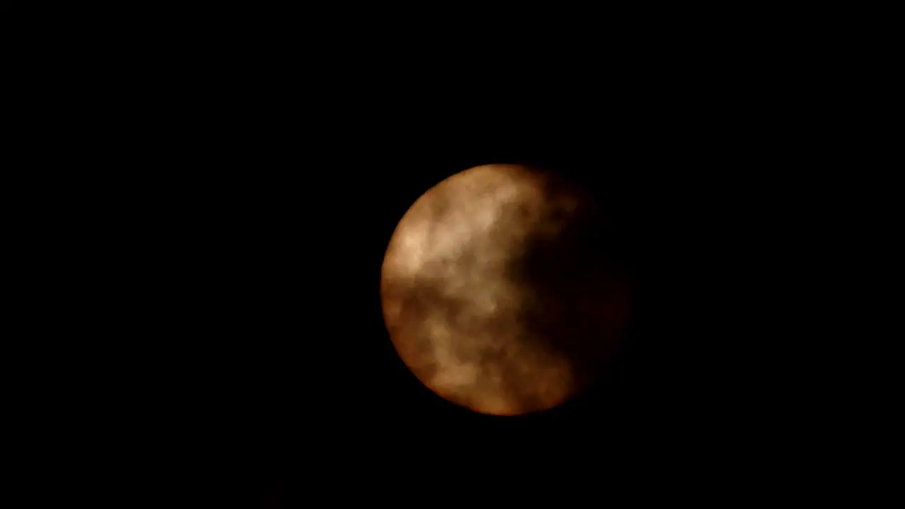 Apocalyptic Scary full moon or sun shining behind dark passing clouds