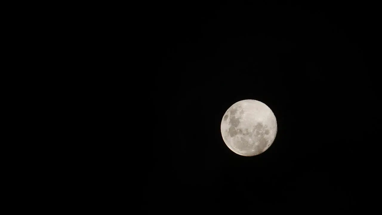 Slow right to left reveal of full moon as clouds pass in front