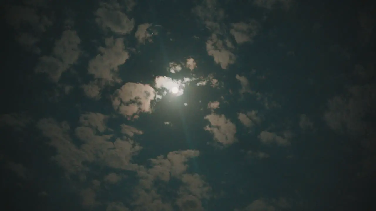 Clouds moving fast and changing forms with full moon in night sky