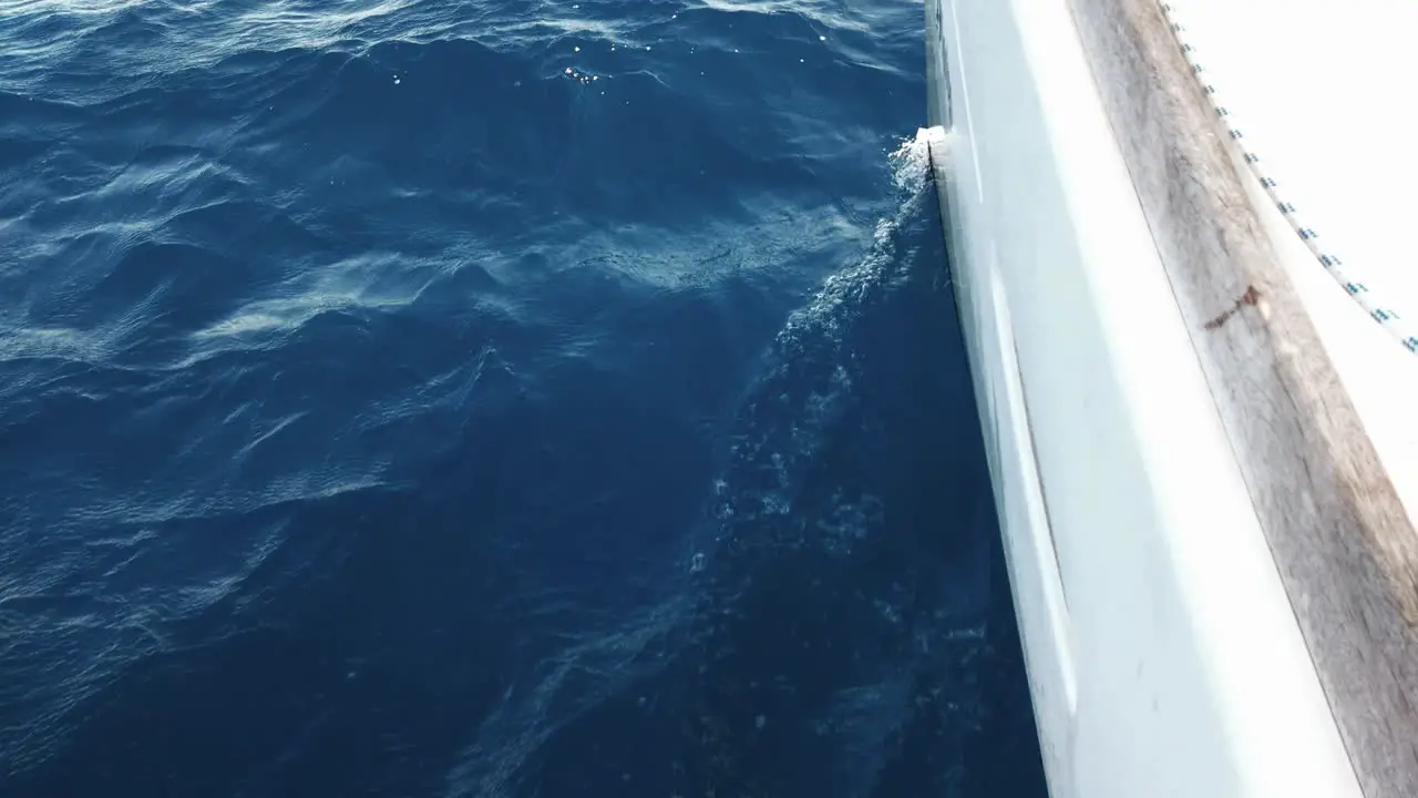 view of a blue slightly dark and wavy sea from a calm sailing white yacht on a sunny summer day