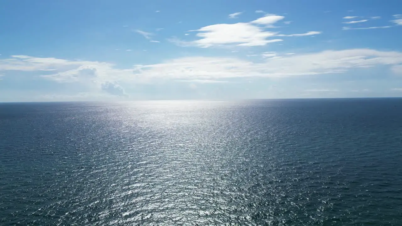 Drone shot moving towards the ocean horizon and sun