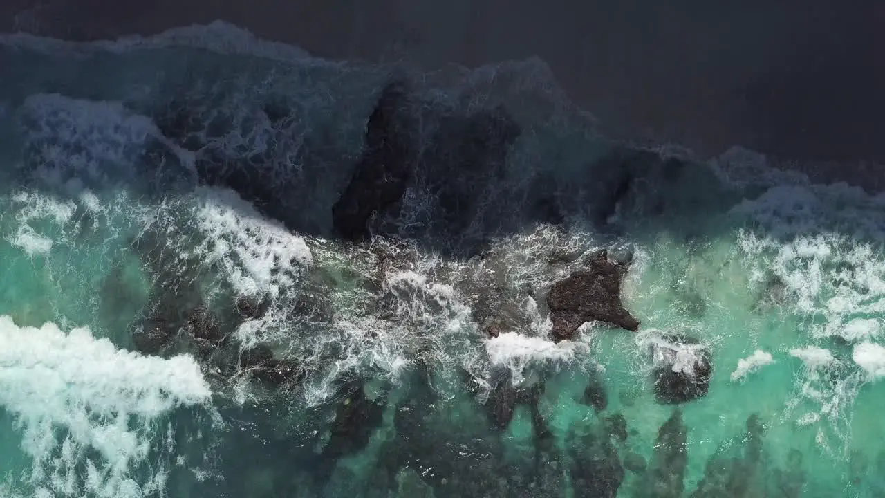 Aerial view of the waves of crystal blue water hitting the shore line of diamond beach in Nusa Penida Indonesia