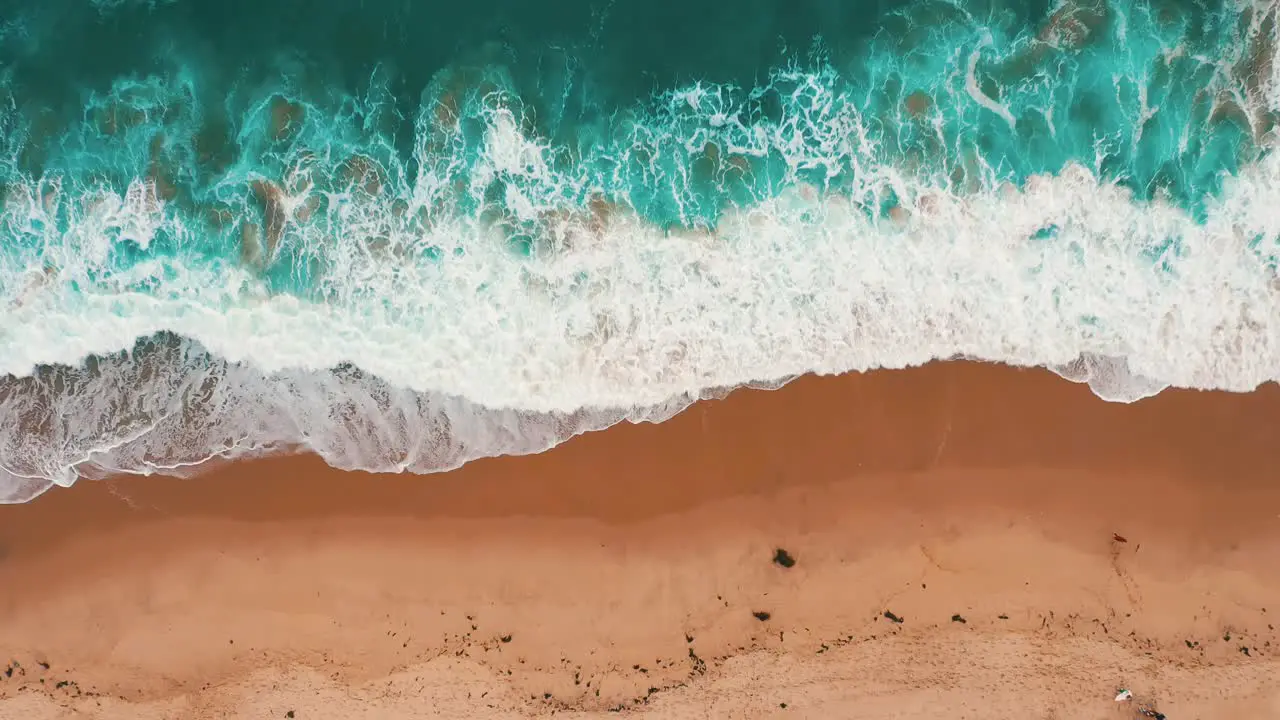 Foamy Waves Coming Onto The Brown Sandy Beach