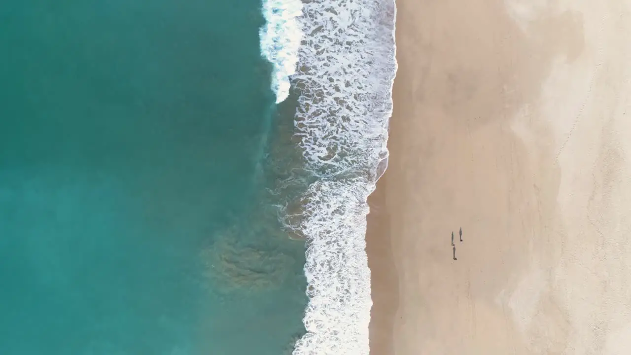 Aerial view of turquoise blue sea waves breaking on the sand of a beautiful white sandy beach