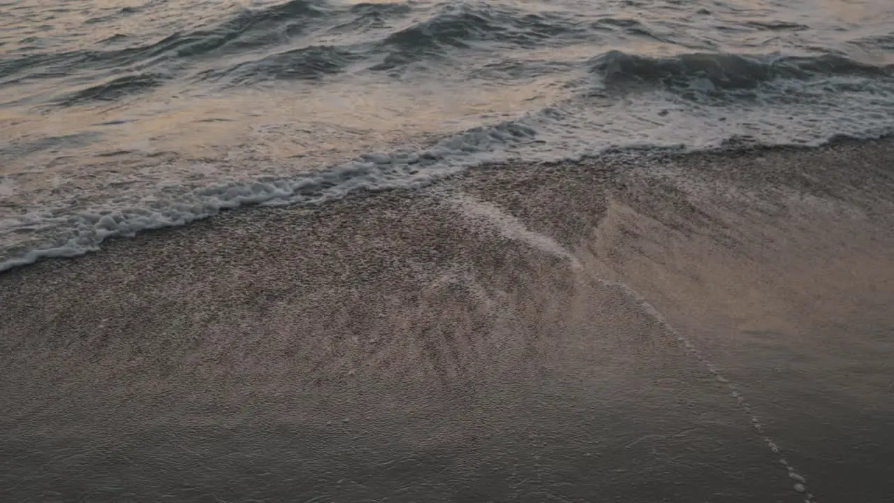 Water receding toward the sea as subsequent Pacific waves burst at the sandy La Punta beach in Mexico during sunset