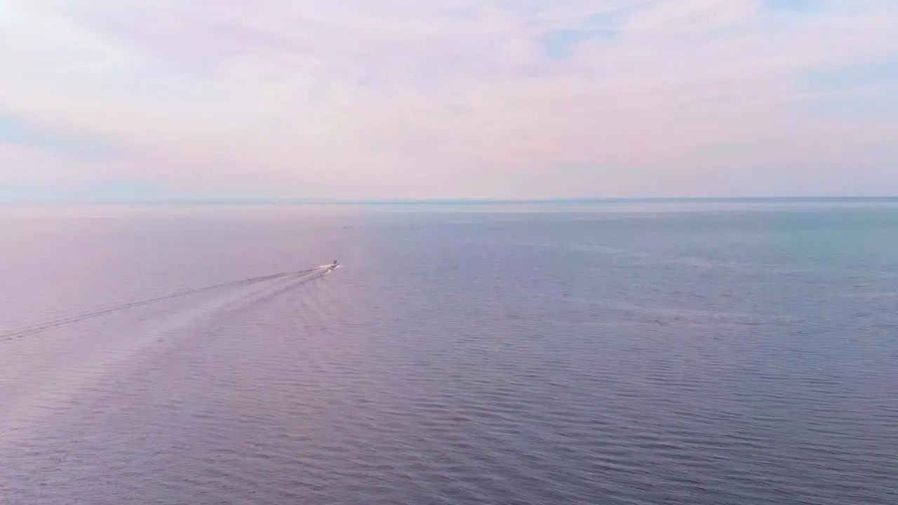 Aerial Shot Of One Boat Sailing In Heart Of Blue Ocean Creating Long Trail Foam