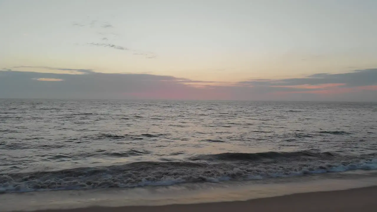 Establishing shot of waves slowly lapping on warm beach in rural mexico during sunset