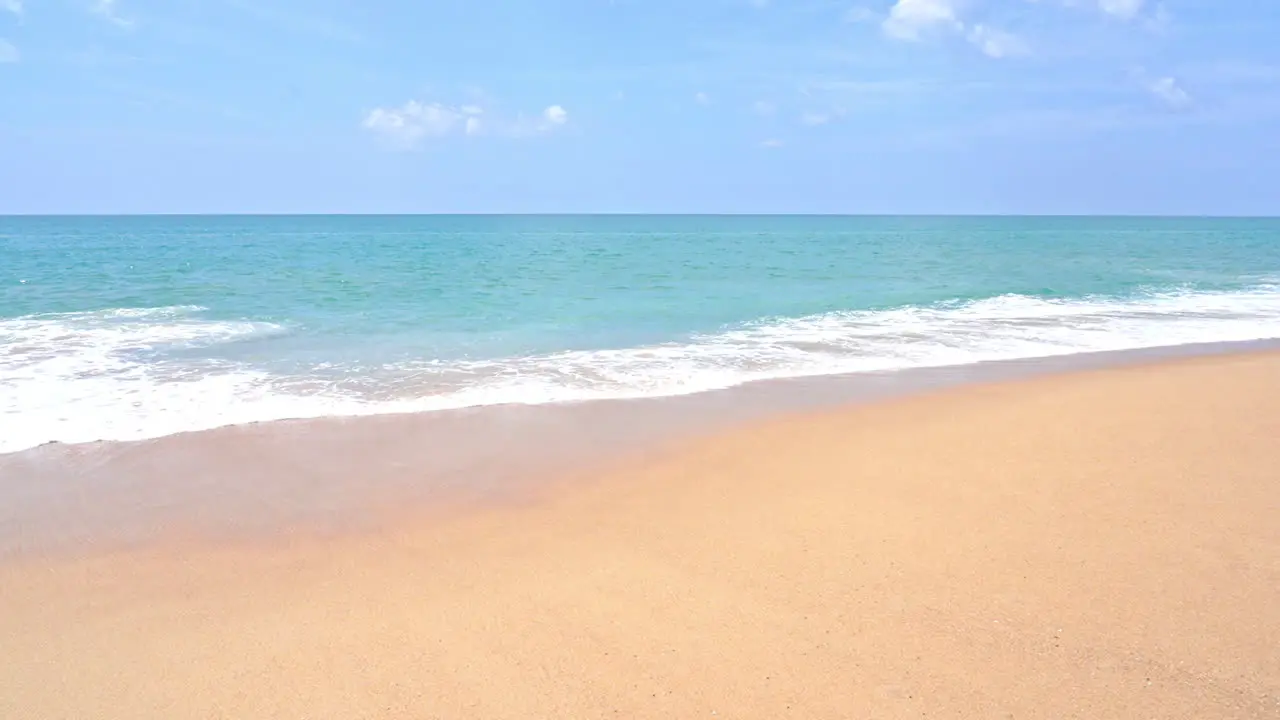 Slow-motion waves slowly spread across a golden sand beach