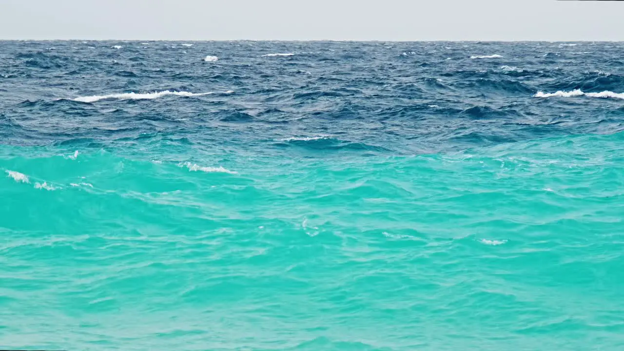 Close up zoom of rough stormy waves during small storm over Caribbean island with blue turquoise ocean and deep blue dark