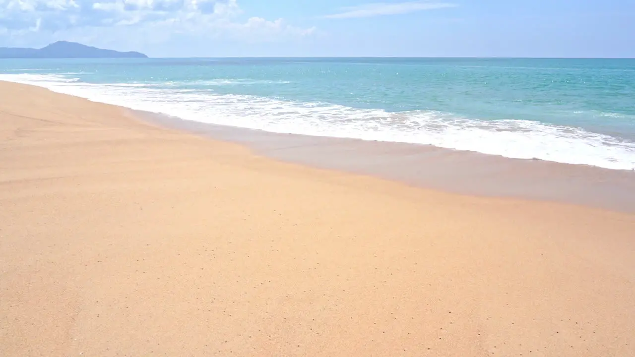 Slow-motion ocean waves skirting along the edge of a sandy beach