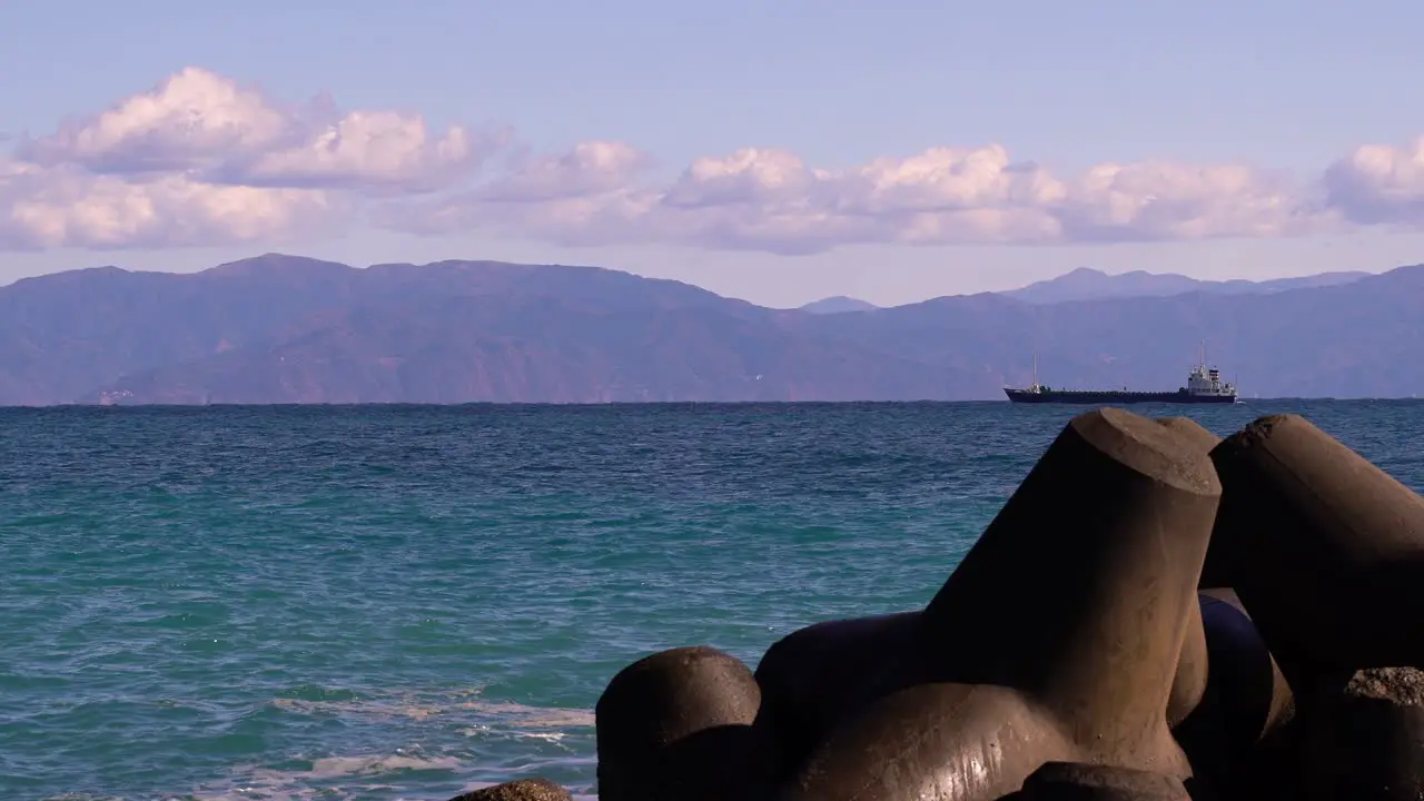 Cargo ship riding on ocean horizon line with mountains in background