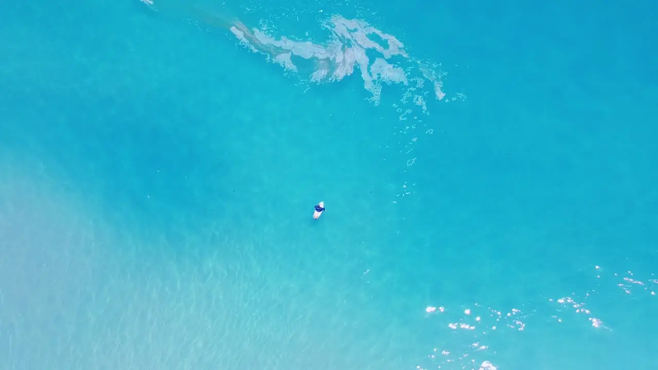 Surfer waiting on waves in aqua coloured ocean