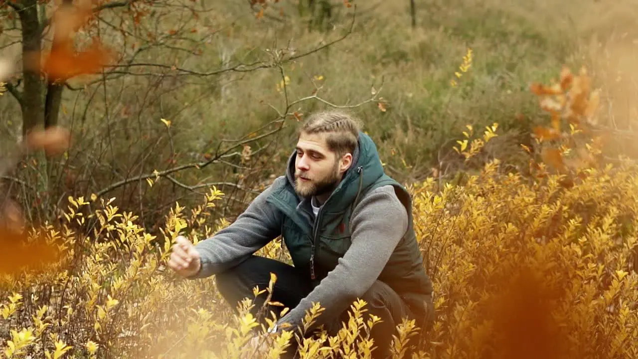 Man sitting in a field with yellow flowers while smoking tabacco