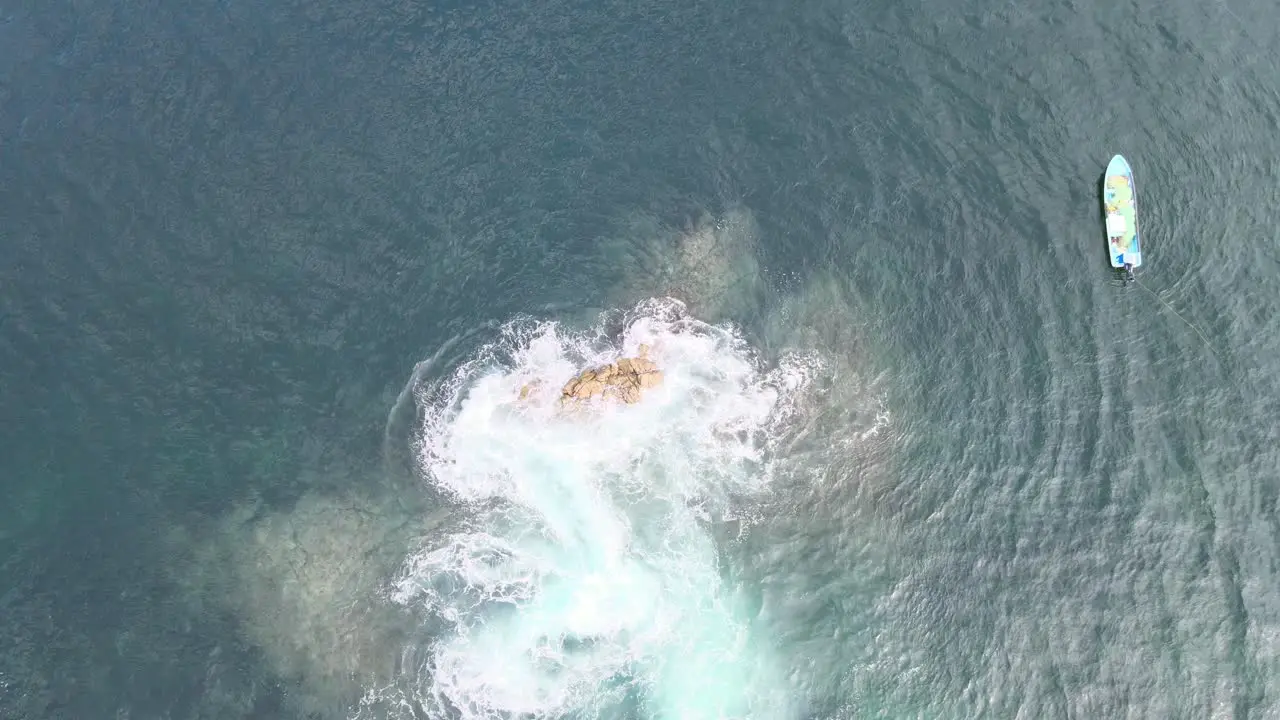 Jib up above rocks in the ocean with two boats