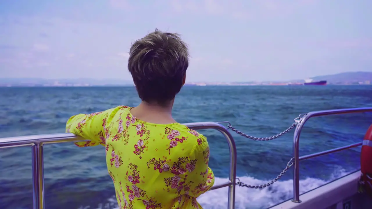 Rear back view of woman looking at the view from a boat