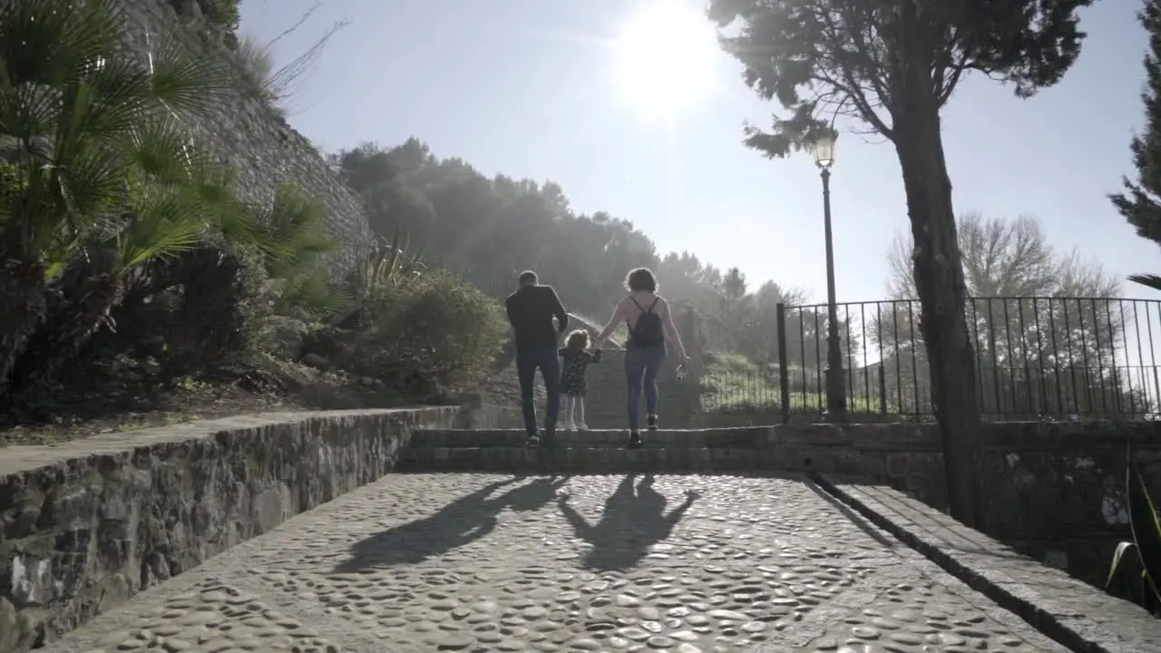 Slow motion dolly shot of a family of mother and father with their small child on a viewing platform in medina sidonia during a sunny day