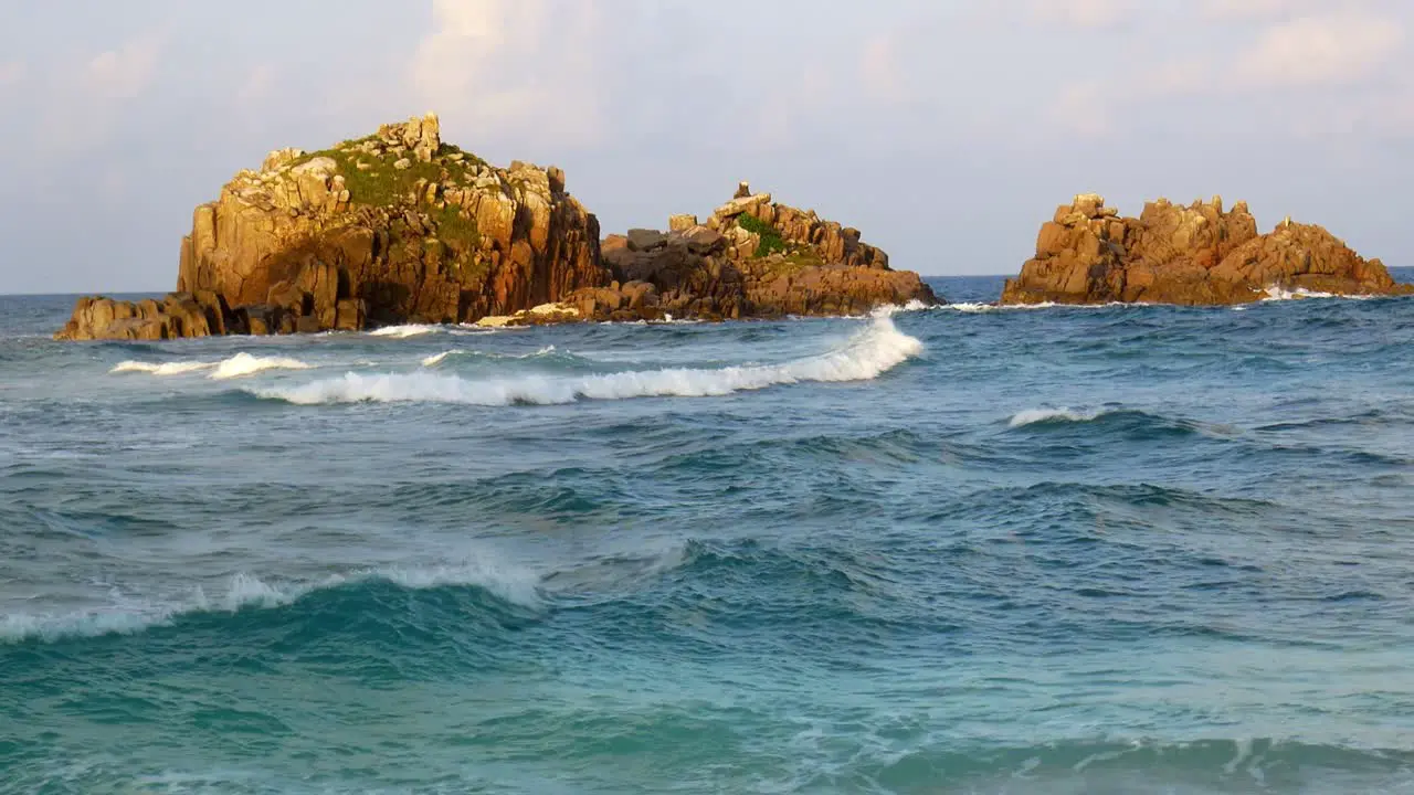 Waves crashing against giant rock on African shoreline during storm