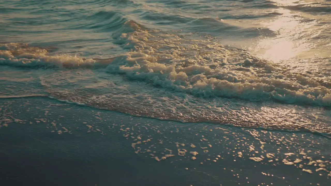 Waves washing up on beach during sunset slow motion